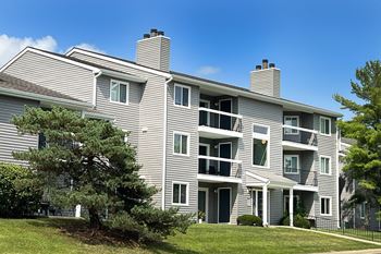 an apartment building with gray siding and a tree in the yard at Deercross Apartments, Cincinnati